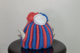 By the Tea Cosy Project - Hand knit tea cosy in bright pink and blue striped colours and flowers in the same colour theme.